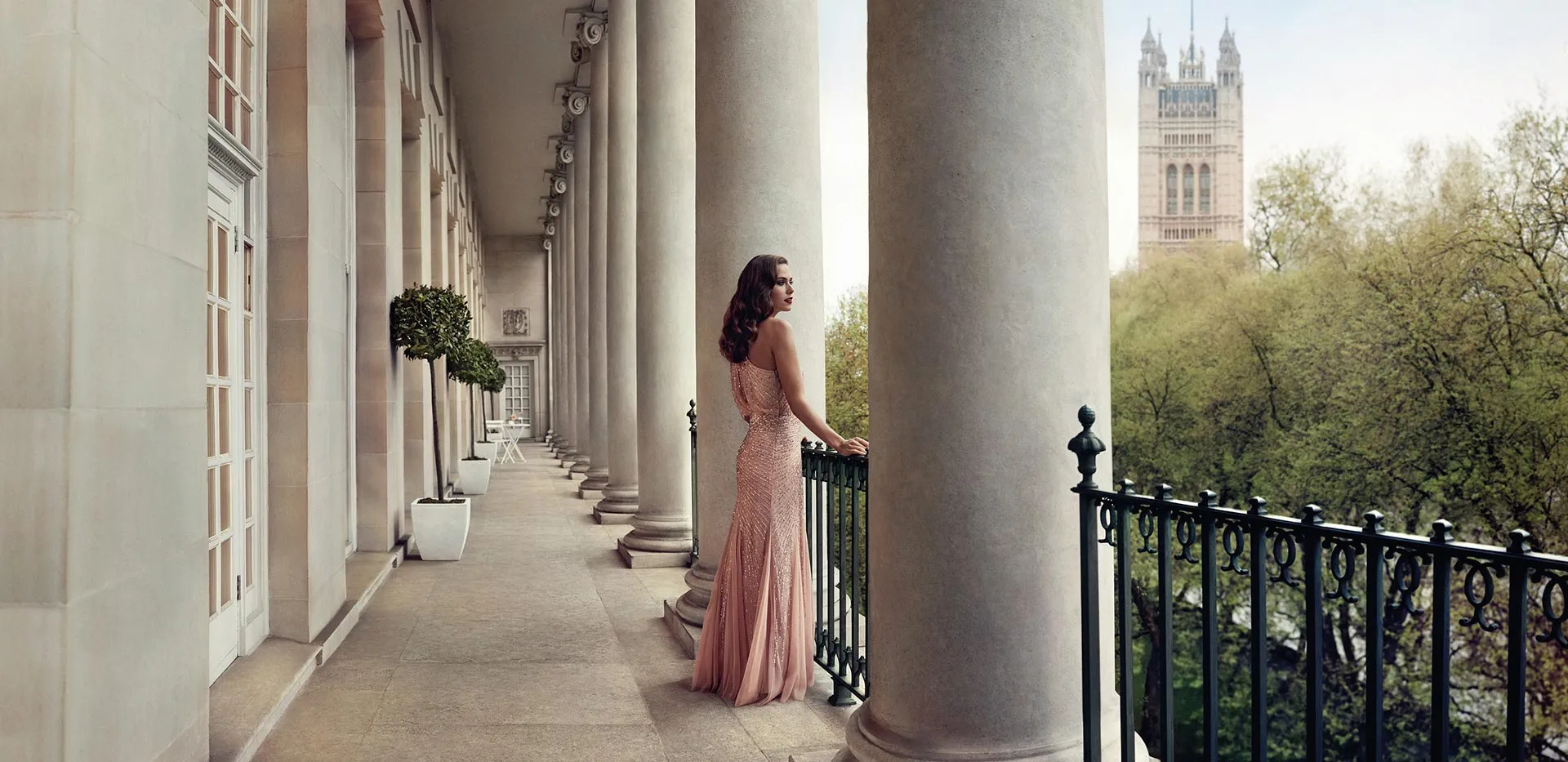 Elegant woman in evening wear on a colonnaded terrace overlooking Westminster, London